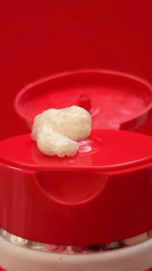 Kırmızı bir arka planda tüpten çıkan köpük yüz yıkama dokusu. Temizleyici ya da cilt bakım ürünü. dikey klip