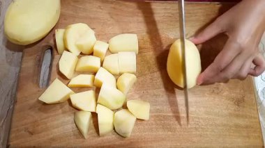Tahta kesim tahtasında patates dilimleme, yanında taze patates parçaları ve yakın menü hazırlama..