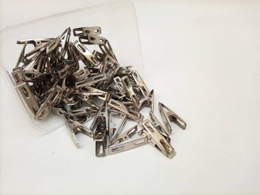 Paslanmaz Çelik Mandallar Beyaz Arkaplan 'daki bir kutudan düşüyor. Ev için metal giysi askıları