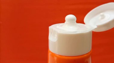Güneş kremi dokusu turuncu arka plandaki tüpten sıkılmış, cilt koruma sistemi yakın.