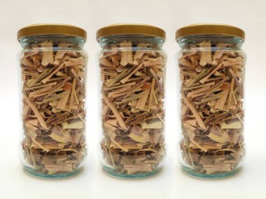 Cam kavanozlar dolusu taze organik limon otu çayı beyaz arka planda, bitkisel bileşenler yakın planda.