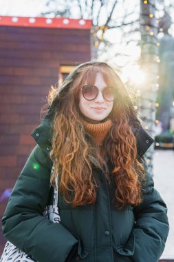 Neşeli kızıl saçlı bir kadın Tiflis, Georgia 'da Avrupa tarzı bir Noel pazarının büyülü atmosferinin tadını çıkarıyor..