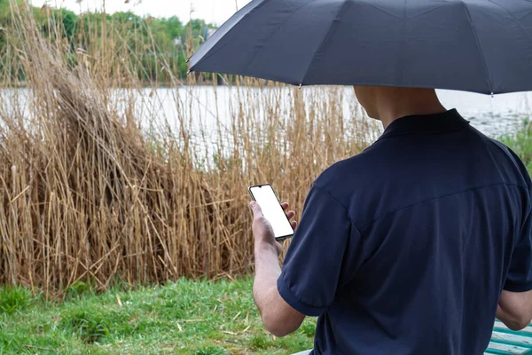 Egy Férfi Esernyő Alatt Egy Partján Használja Okostelefonját — Stock Fotó