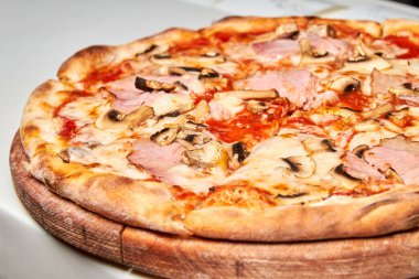Hafif arka planda pastırmalı, domatesli, mantarlı ve peynirli taze pizza. Yakın çekim, seçici odaklanma