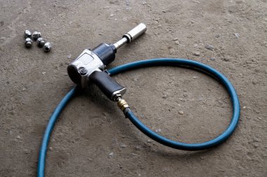 Yedek lastikler için pnömatik anahtar ya da arka bahçe mekaniği çarpma anahtarı yerde yatıyor..