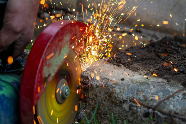 Cutting a metal pipe with a circular saw with splashes of sparks. Garden work