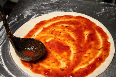 İtalyan pizzası hazırlarken domates sosu ekliyorum.