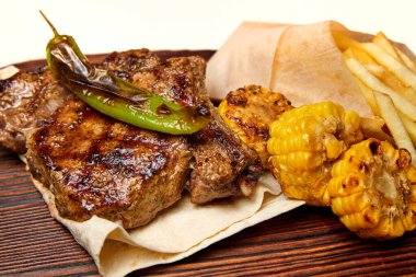 Izgara domuz pirzolası, mısır ve kızarmış patates. Yakın çekim, seçici odaklanma