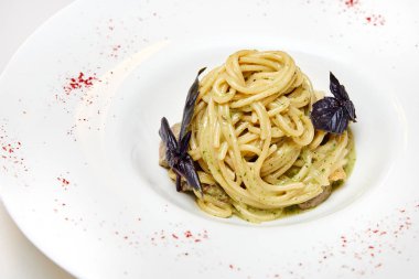 Dana etli makarna ve beyaz tabakta pesto sosu.