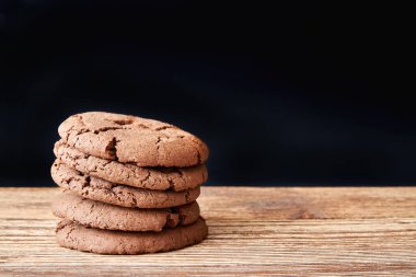 Ahşap masa ve arka planda birikmiş kurabiyeler.