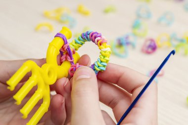 Lastik bantlı dokuma. Dokuma tezgahıyla lastik bantlar örüyorlar. Lastik bileklik takan bir kızın elleri.