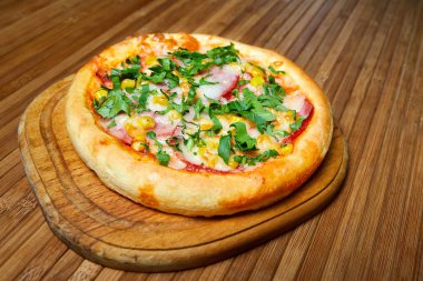 Peynirli pizza, domuz pastırması ve ahşap tabakta otlar. Yakın çekim, seçici odaklanma