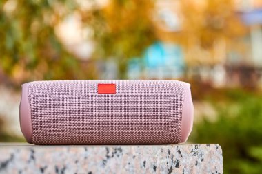 Şehirdeki taşınabilir pembe kablosuz hoparlör granit yüzeyde. Yakın çekim, seçici odaklanma