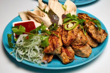 Domuz şiş kebap, lavaş, soğan turşusu ve kırmızı sos.