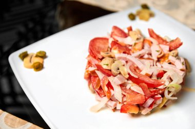 Domuz filetosu salatası, domates, mantar turşusu, soğan ve kapari. Yakın çekim, seçici odaklanma