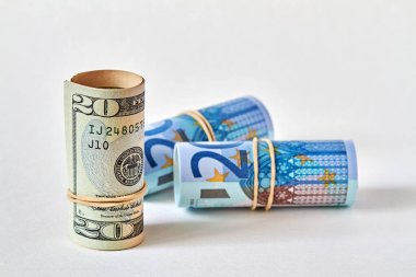 20 dolarlık banknot, arka planda duran 20 avroluk banknotlar gibi yuvarlandı. Dolar üstünlüğü kavramı avrodan üstündür. Yakın çekim, seçici odaklanma