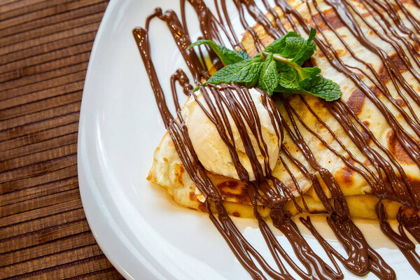 Блинчик с шариком мороженого и шоколадом. Крупный план, избирательный фокус