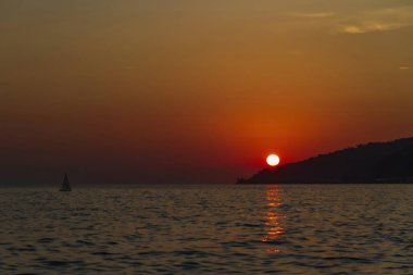 Gün batımında denizde küçük bir yelkenli