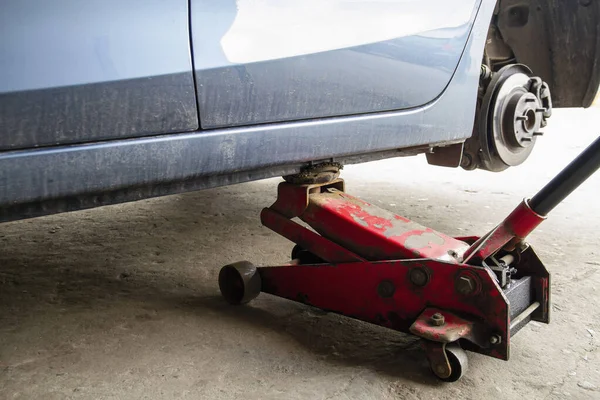 Replacing wheels on a car, jack holds the body in raised position. Car without wheel and lift up by hydraulic, waiting for tire replacement.