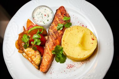 Fırında sebzeli somon bifteği, patates püresi ve sos.