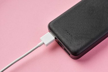 USB konnektörü pembe arka planda Power Bank 'a bağlı. Cihazları şarj ediyorum. Yakın çekim, seçici odaklanma