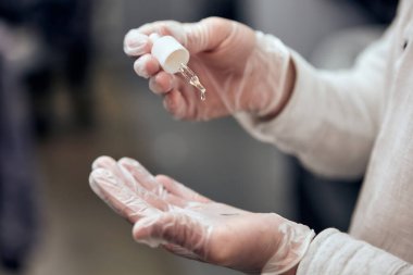 Berber, barbar dükkanındaki adam için sakal yağını damlatıcıyla sürüyor. Yakın çekim, seçici odaklanma