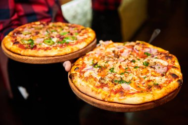 Garson arka planda pastırmalı, mantarlı ve peynirli taze pizzalar tutuyor. Yakın çekim, seçici odaklanma