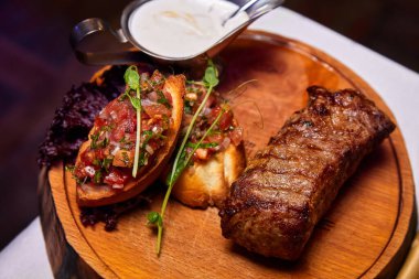 Ahşap tabakta domates salsa soslu ızgara dana biftek. Yakın çekim, seçici odaklanma