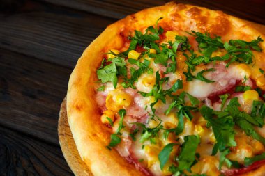 Peynirli pizza, domuz pastırması ve ahşap tabakta otlar. Yakın çekim, seçici odaklanma