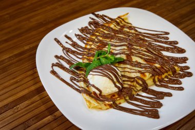 Bir kepçe dondurma ve çikolatalı krep. Yakın çekim, seçici odaklanma