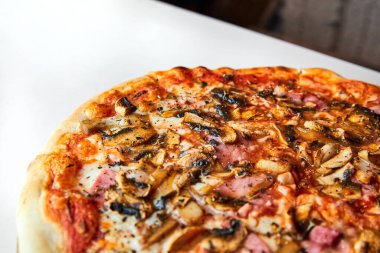 Hafif arka planda pastırmalı, mantarlı ve peynirli taze pizza. Yakın çekim, seçici odaklanma.