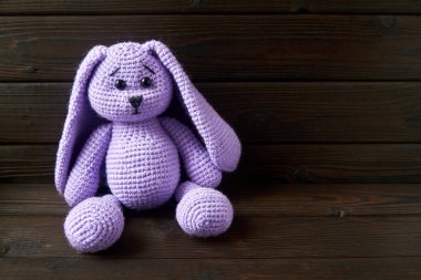 El yapımı mor bir bebek. Kahverengi ahşap arka planda tavşan oyuncağı.