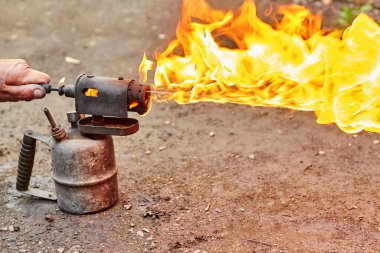 Erkek el eski paslı kaynak makinesinde alevi ayarlar.