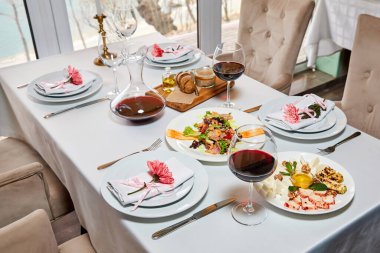 Kırmızı şarap ve aperatif dolu dekore edilmiş bir restoran masası misafirleri bekliyor. Yakın plan.