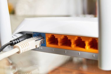 Kabloyla internete bağlı cam bir masadaki beyaz kablosuz yönlendirici. Yakın plan.