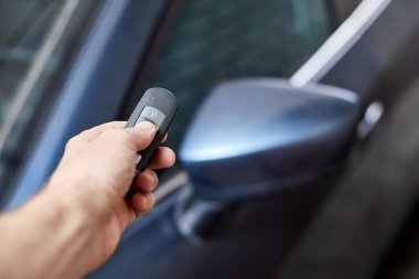 Araba sahibi elinde anahtarsız giriş için bir uzaktan kumanda cihazı tutuyor. Yakın çekim, seçici odaklanma
