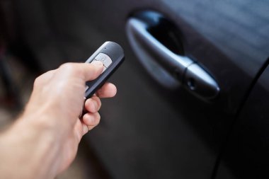 Araba sahibi elinde anahtarsız giriş için bir uzaktan kumanda cihazı tutuyor. Yakın çekim, seçici odaklanma