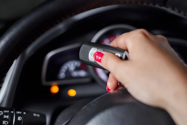 The car owner holds in his hand a remote control device for keyless entry against the background of the car dashboard