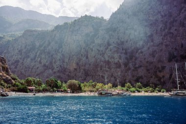 Türkiye 'nin Kelebek Vadisi' nde, sarp kayalıkların yanındaki kayalıkların yanında kayalıkların ve yemyeşil ağaçların bulunduğu manzaralı kıyı manzarası 