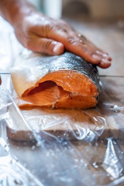 Ahşap bir tahtanın üzerinde taze somon fileto, gerçekçi stil, kapalı mutfak arka planı, gıda hazırlama kavramı