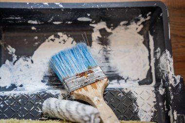 Dağınık boyalı bir yüzeye mavi tüylü boya fırçası ve paslı ferruat, desenli siyah arka planda yakın plan fotoğrafı, DIY konsepti