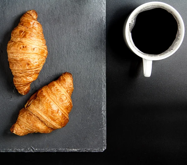 Breakfast with croissants, black coffee on granite stone plate b