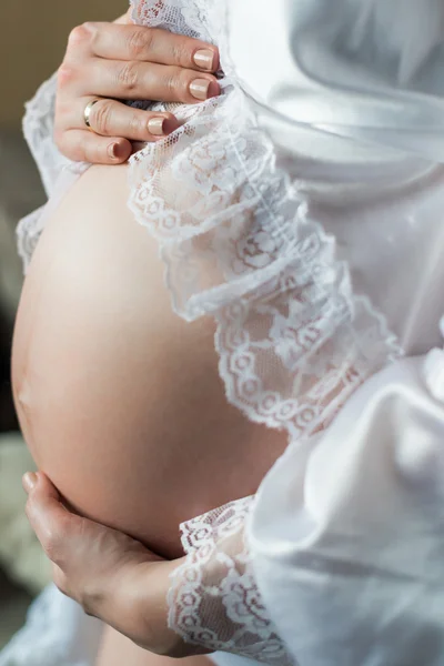 Femme enceinte tenant ses mains sur le ventre à la maison — Photo