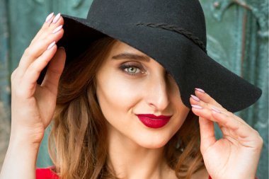 Siyah şapkalı, kameraya bakan güzel, modaya uygun beyaz kadın portresi.