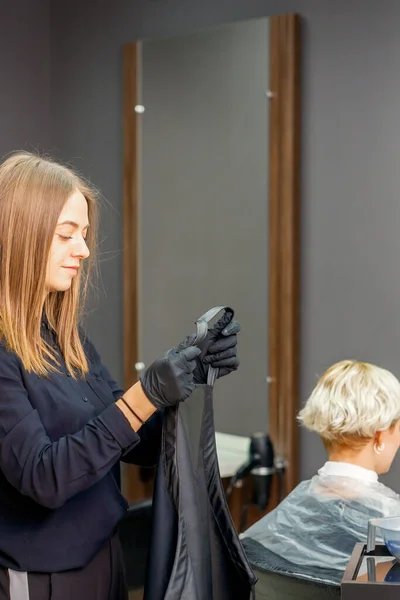 Kobieta Fryzjer Przygotować Stawia Czarną Pelerynę Klienta Kobiety Salonie Piękności — Zdjęcie stockowe