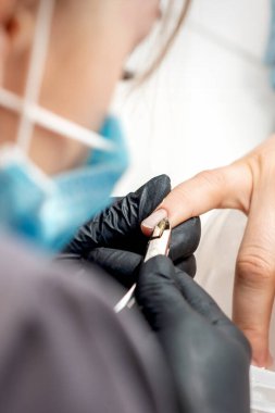 Manikür ustası tırnaklarını profesyonel tırnak makasıyla söker. Tırnak törpüsü salonundaki kadın tırnaklarında.