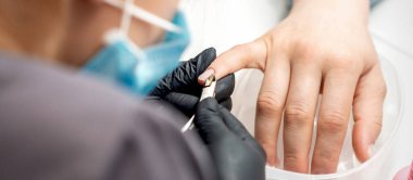 Manikür ustası tırnaklarını profesyonel tırnak makasıyla söker. Tırnak törpüsü salonundaki kadın tırnaklarında.