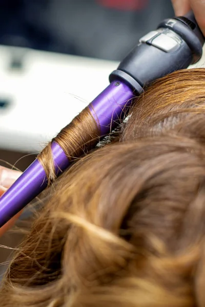 미용실에 여자의 머리를 줄임으로써 머리를 곱슬머리로 만드는 직업적 미용사 — 스톡 사진