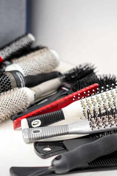 Set of different hair brushes and combs lying on the white table