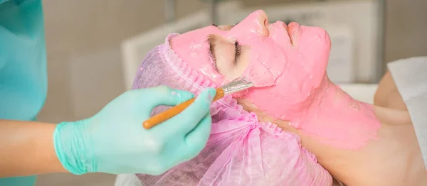 Mão Cosmetologist Que Aplica Máscara Algínica Rosa Cara Mulher Jovem — Fotografia de Stock